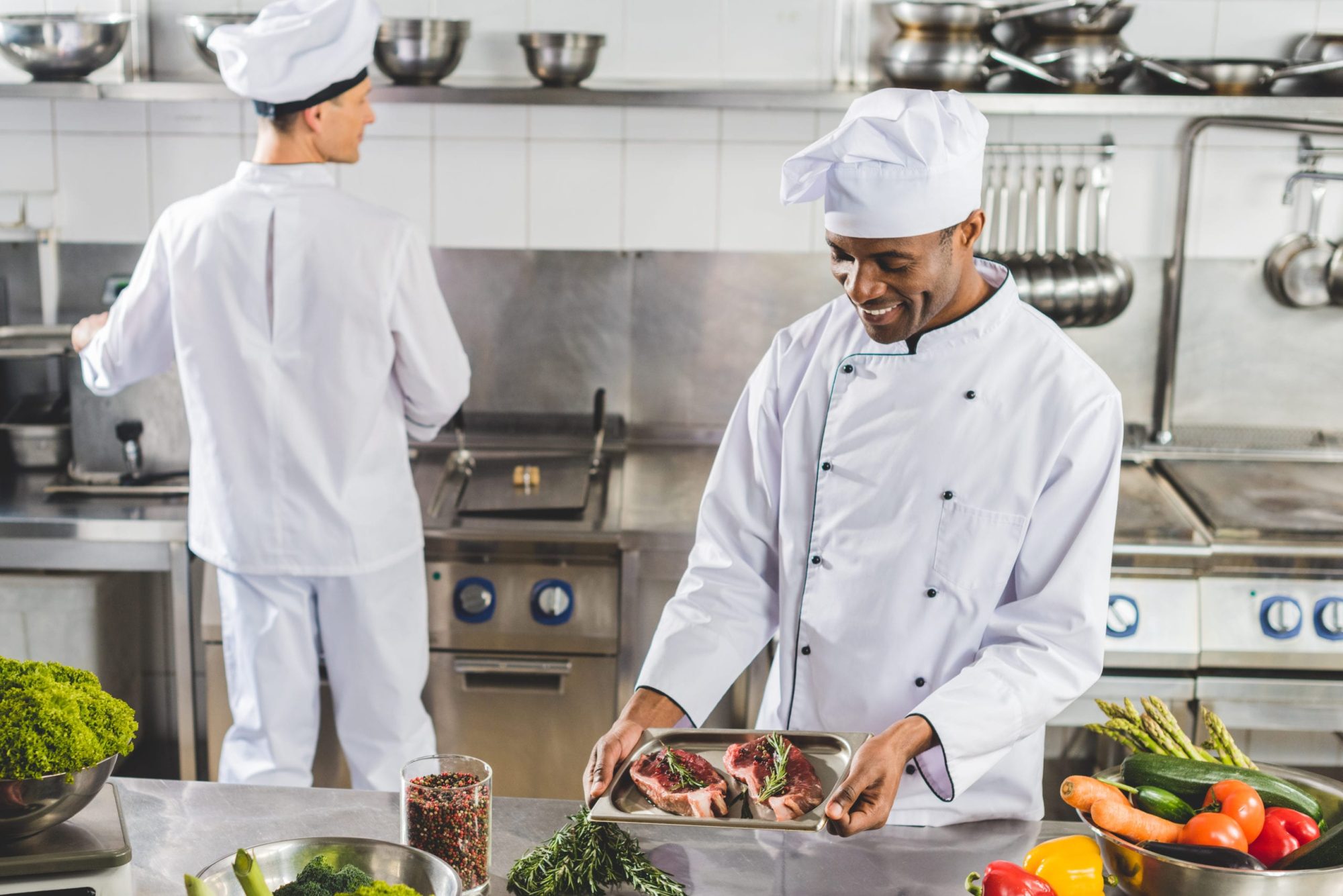 Multicultural,Chefs,Cooking,Meat,With,Vegetables,At,Restaurant,Kitchen